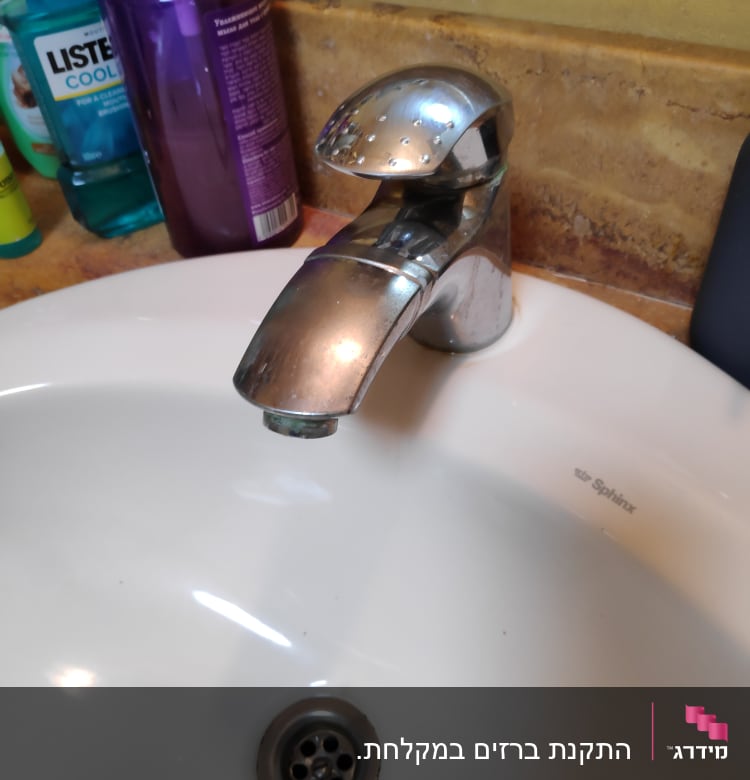 ברז כרום מעל כיור לבן עם ניקוז מתכת